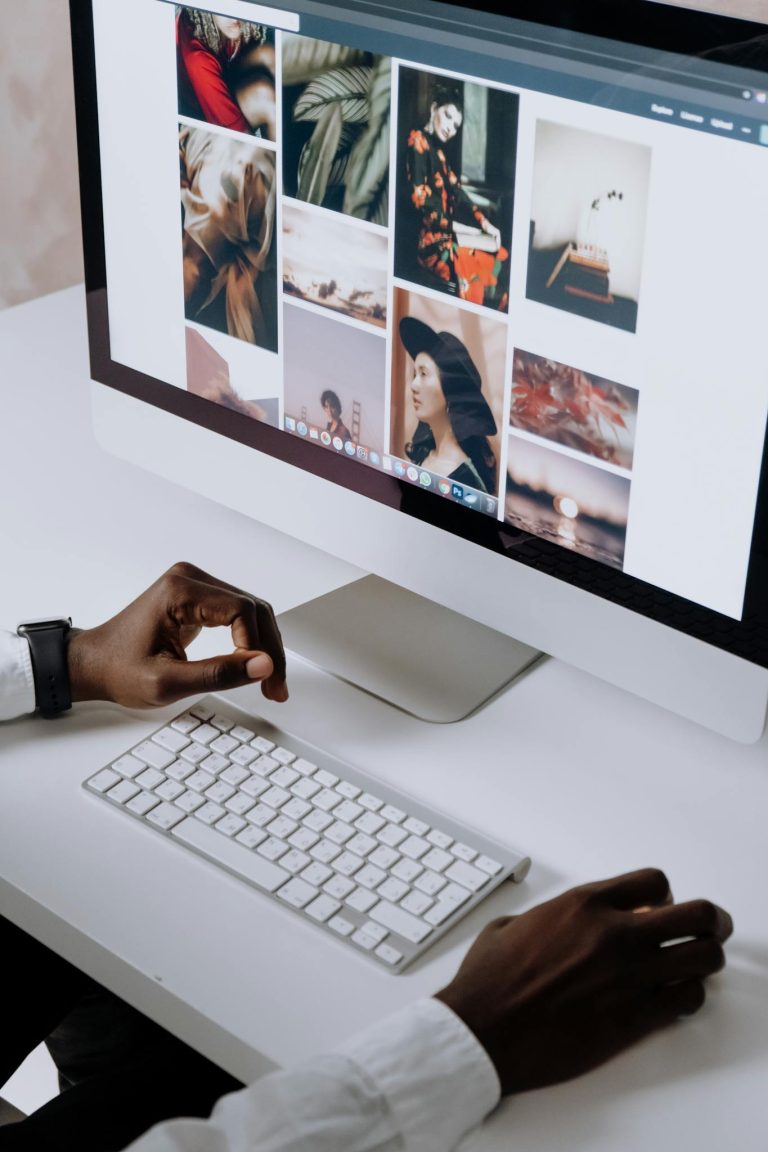 Man working on computer in modern office, viewing photography website. Clean and tech-focused environment.